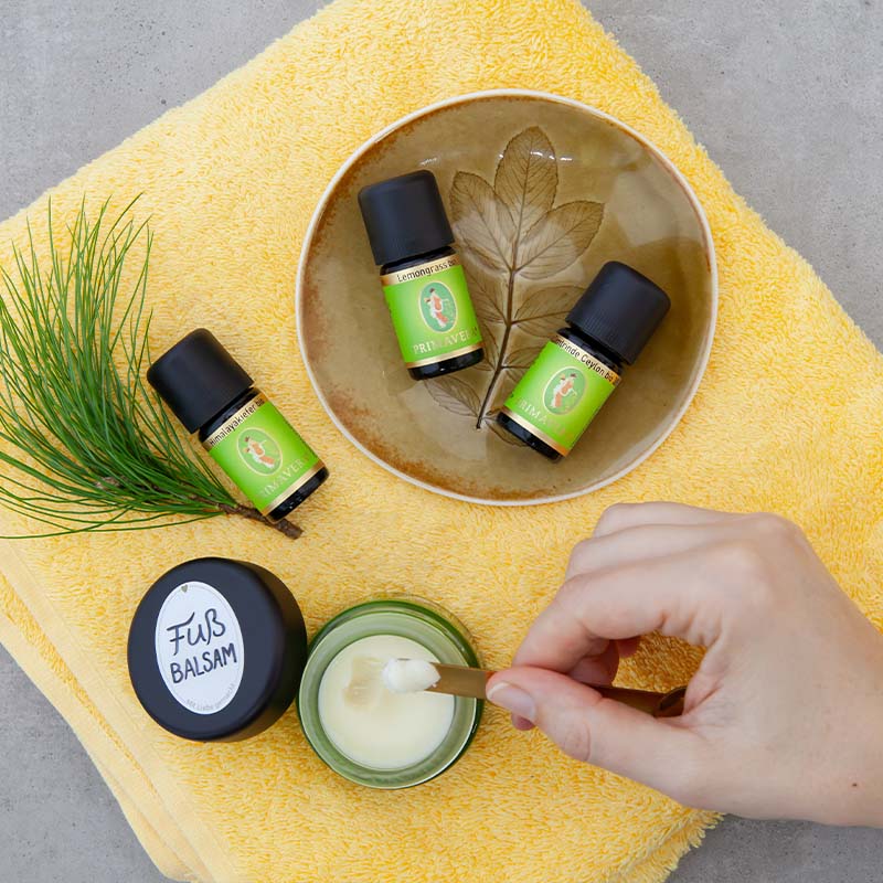 3 Ätherische Öle und fertiger Fußbalsam wird mithilfe eines Holzstils herausgenommen.