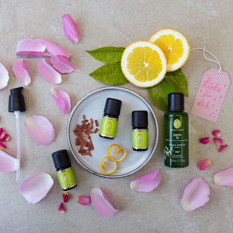 PRIMAVERA Jojobaöl, ätherische Öle und Dosierpumpe, dekoriert mit Rosenblüten und Zitrusfrüchten