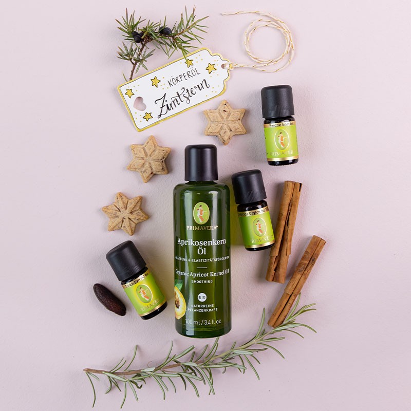 Primavera Aprikosenkernöl und ätherische Öle, dekoriert mit Zimtstangen, Sternplätzchen und Rosmarinzweigen.